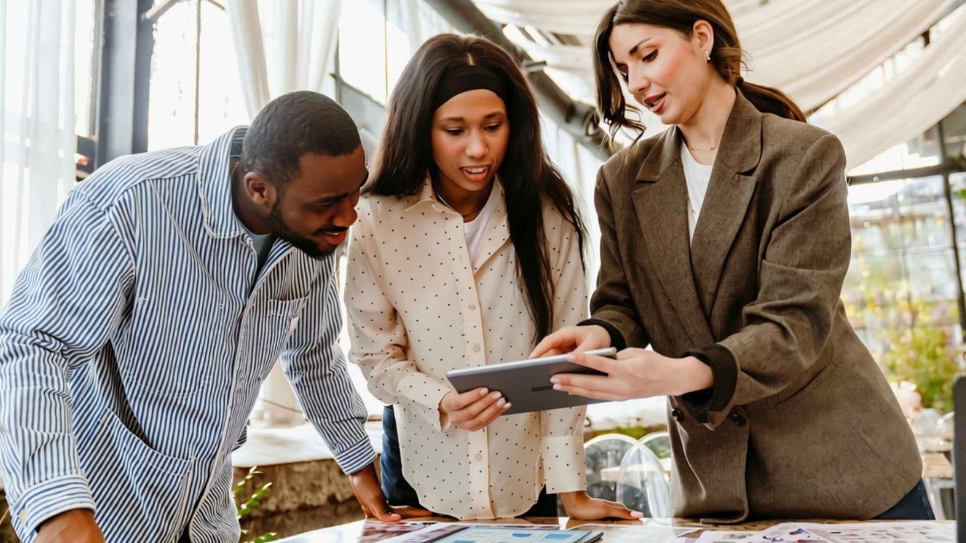 Three people reviewing information together on a tablet.